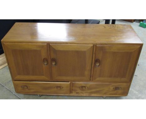 Ercol Windsor light elm sideboard, with three doors and two doors with oval handles, on casters, W130cm D45cm H76cm 