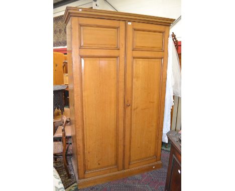 A large light oak double wardrobe, stepped cornice, fielded panel doors, plinth base. 212cm high x 131cm wide x 61cm deep.