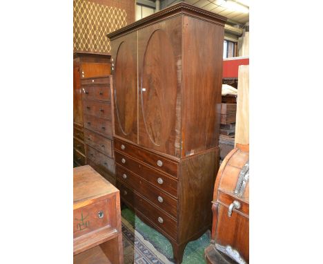 A George III linen press, outswept cornice, two crossbanded oval panelled doors to top, four graduated drawers to base, oval 