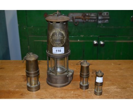 A brass Eccles miner's lamp; a set of three miniature graduated brass miner's lamps (4)