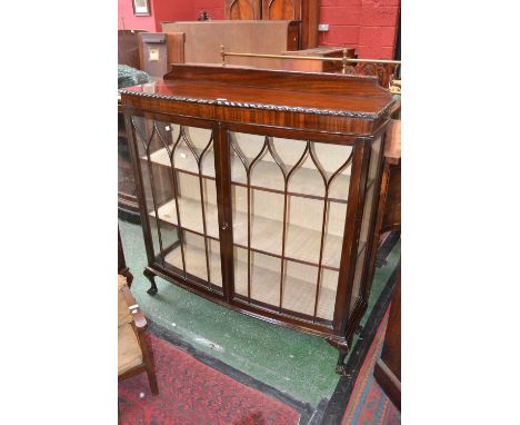 A 1940's bow front china display cabinet, shaped gallery, gadrooned oversailing top, two astragal glazed doors enclosing shel