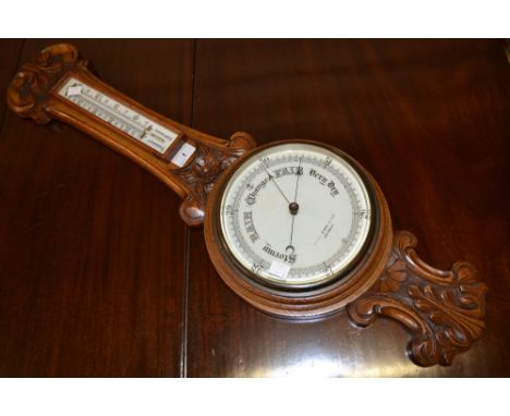 An Edwardian carved oak barometer/thermometer, retailed by Gamages, London, white scale and dial, floral carved case, c.1900