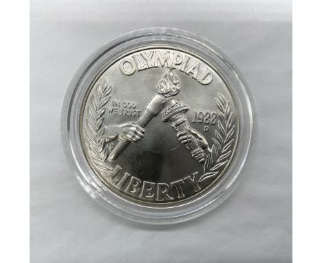 Denver Mint. The obverse side features two hands, one holding the Statue of Liberty torch and the other is holding the Olympi