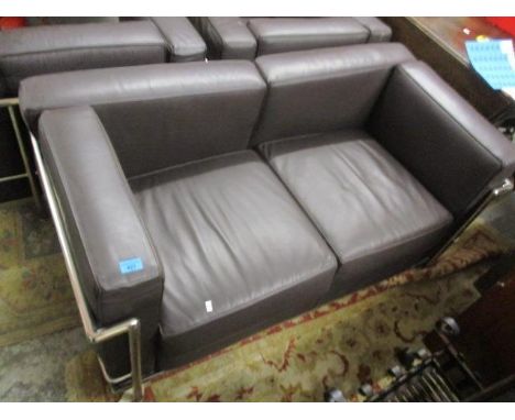 A brown leather two seater sofa with a chrome frame and two matching armchairs 
