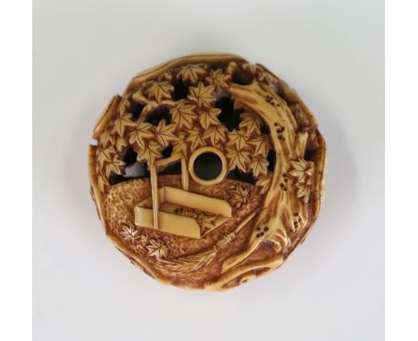 A Japanese carved, pierced and stained ivory manju netsuke, Meiji period, finely carved to the top with a dustpan and brush, 