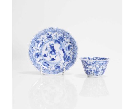 A Chinese blue and white cup and saucer, Kangxi (1662-1722), of lobed form, the cup painted with ladies and flowers from the 