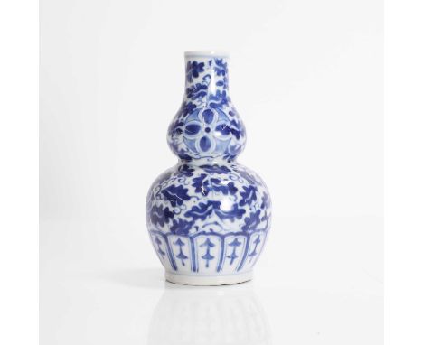 A Chinese blue and white double gourd vase, Kangxi (1662-1722), painted with florets amongst leafy tendrils, 15cm high清康熙 青花缠
