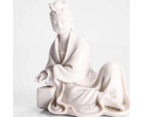 A Chinese blanc de Chine figure, Republic period (1912-1949), of guanyin seated with his right hand resting on a pile of book