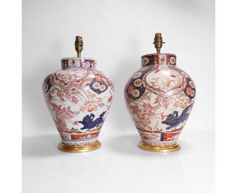 A pair of Japanese Imari vases, early 18th century, each of tapering form, painted with Buddhist lions playing amongst flower