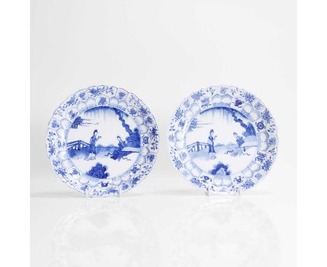 A pair of Chinese blue and white plates, Kangxi (1662-1722), each of lobed circular form, painted with ladies in a garden enc