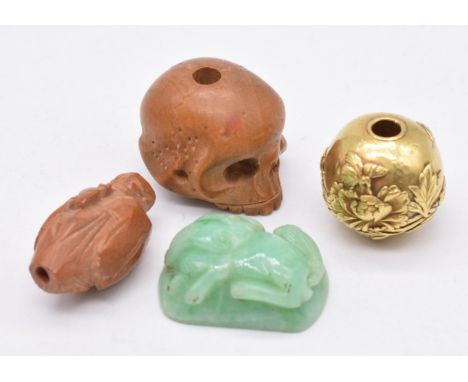 Chinese sandalwood netsuke in the form of a skull, Chinese carved jade phoenix, Chinese yellow metal bead and a carved nut in