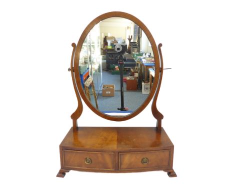 A reproduction bow-fronted mahogany toilet mirror: oval plate and two half-width drawers, raised on pronounced and shaped oge