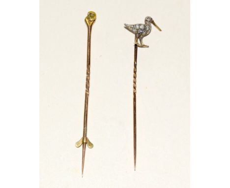 Two yellow metal stick pins. One in the form of a bird diamond set