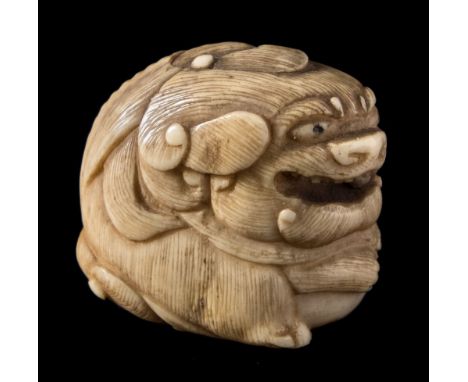 A Japanese carved ivory netsuke: of a mythical beast with a small loose ball in it's open mouth, a larger ball clasped betwee