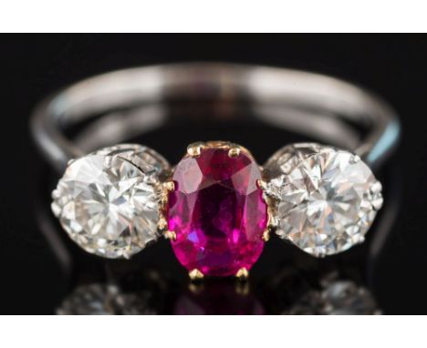 A ruby and diamond three-stone ring: the oval ruby approximately 7.2mm long x 5.3mm wide x 2.7mm deep between circular, brill