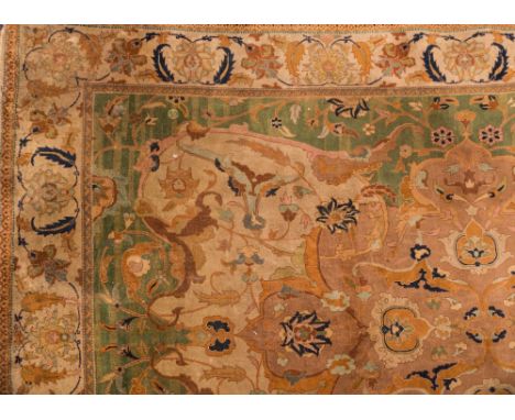 An Indo Persian carpet:, the field with a central brown cartouche medallion and palmette and floral foliate scroll designs, w