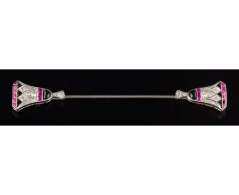 An Art Deco black onyx, diamond and ruby jabot pin: with stylised Egyptian lily terminal motifs, 76mm long (one ruby deficien
