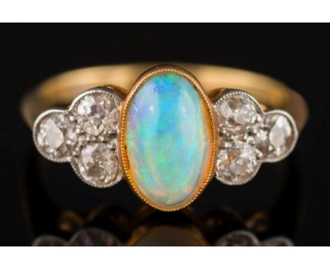 An 18ct gold, opal and diamond seven stone ring: the central oval opal approximately 9.2mm long x 5.2mm wide x 3.7mm deep and