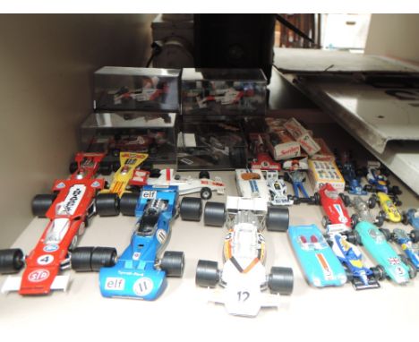 A shelf of Corgi, Dinky, Polistil, Zylmax and similar Formula 1 racing cars, some with boxes or display cases