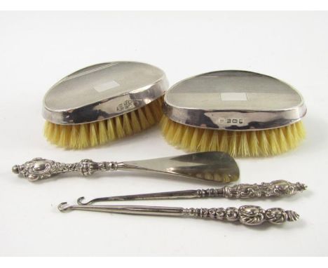 A pair of silver backed hair brushes, with engine turned decoration, Birmingham 1979, and two button hooks and a shoe horn wi