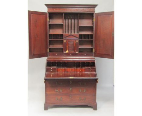 A George III mahogany bureau cabinet, the outswept pediment above two doors enclosing shelves, and recesses flanking an archi