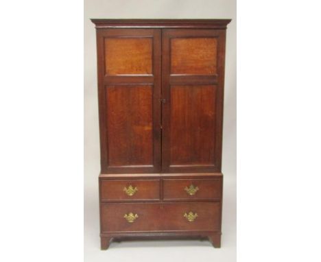 A George III oak linen press, the pediment over two doors enclosing three shelves, above two short and one long deep drawers,