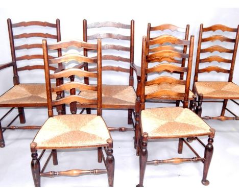 A harlequin set of six oak ladder back dining chairs with rush seats, comprising a pair of carvers and four single chairs.