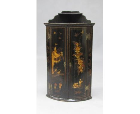 A Regency Japanned lacquer bow fronted wall mounted corner cupboard, the single shelf back over a pair of doors decorated wit