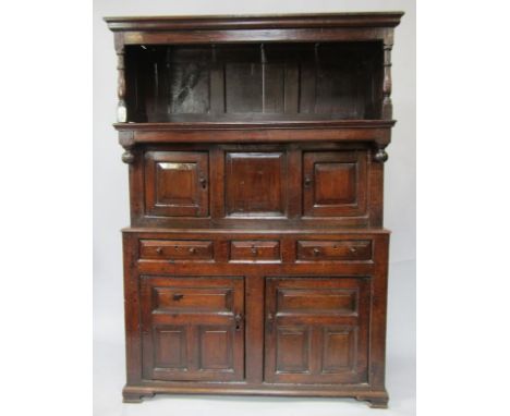 An early 18thC Welsh oak Ewpwrdd Tridarn, the pediment open top with baluster turned columns, over two recessed panelled door