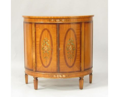 A Sheraton revival demi lune satinwood and painted side cabinet, the top painted with roses, two doors painted with paterae a