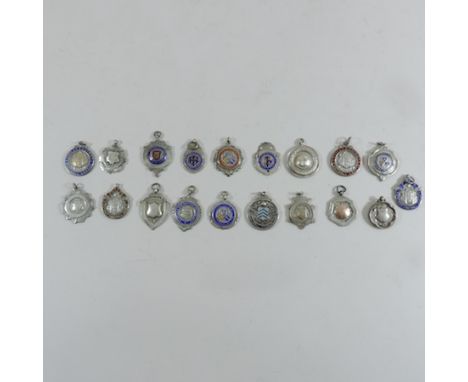 A collection of sporting related enamel badges, some silver