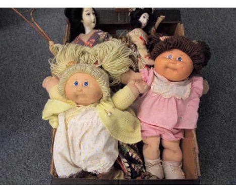 Two dolls wearing Japanese attire and two Cabbage Patch Kids dolls