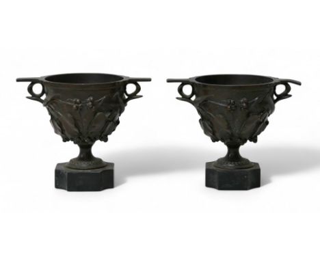 A pair of early 19th century bronze skyphos style cups, both with relief foliate decoration, raised upon quatreform bases, ea