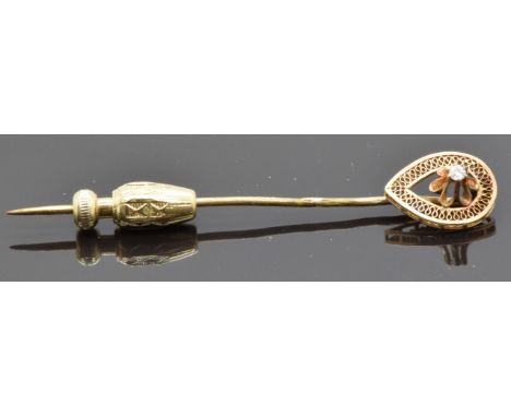 A stick pin set with a diamond within a filigree border&nbsp;