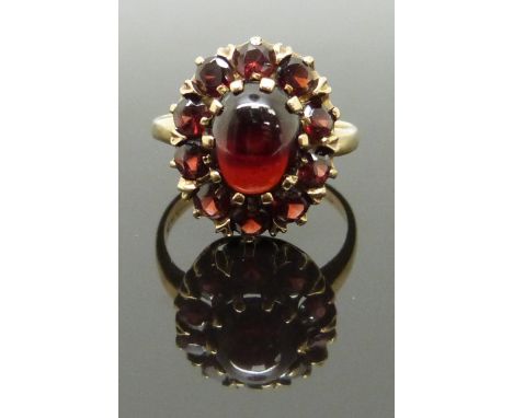 A 9ct gold ring with an opal cabochon surrounded by further garnets, size K, 3.89g&nbsp;