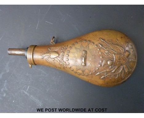 A copper powder flask with embossed decoration of a US crest with shaking hands and eagle above, 23cm long