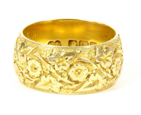 An 18ct gold wedding ring, engraved with flowers and ivy leaves, Birmingham 1912, 10.79g