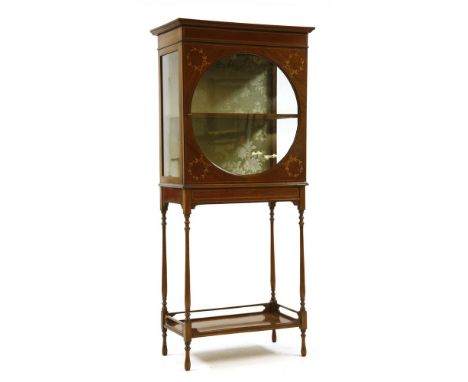 An Edwardian mahogany and inlaid display cabinet , the door with circular glazed panel, on ring turned supports, united by an