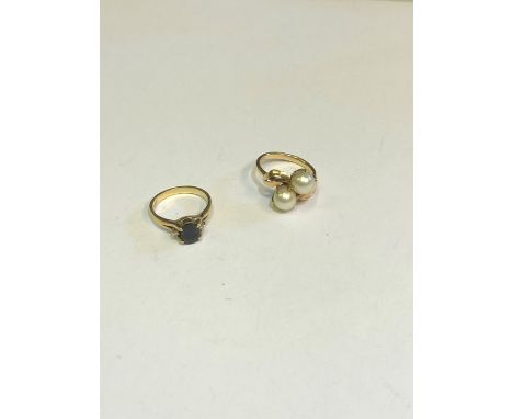 A cross-over ring with two cultured pearls with leaf motif shoulders, yellow metal set stamped 14k, size L to/w a dark blue s