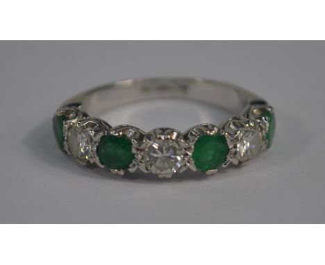 A seven stone half eternity ring set with alternate four circular emeralds and three circular diamonds, 18ct white gold, size