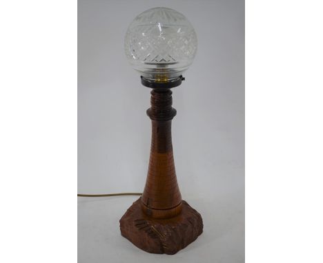 A Cornish turned, carved and incised wooden table lamp in the form of a lighthouse, with glass shade, 53 cm h o/a