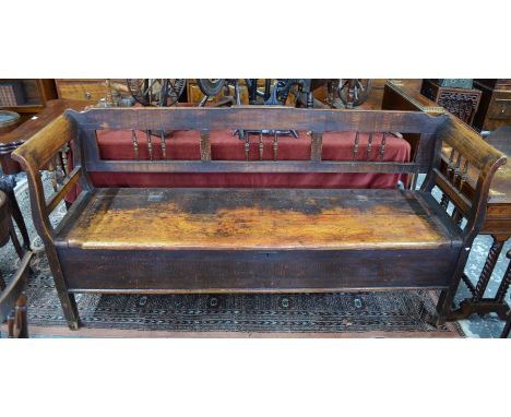 An antique continental fruitwood box settle / bench, the part spindle back over a hinged storage well, on stile feet, 192 cm 