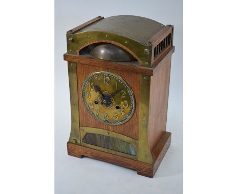 An Arts &amp; Crafts brass mounted oak cased mantel clock, the 14-day strike German H.A.C. movement striking the half hours o