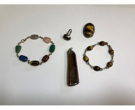 A small collection of tiger's eye jewellery including a long assymetrical pendant, oval brooch, oval ring and chain linked br