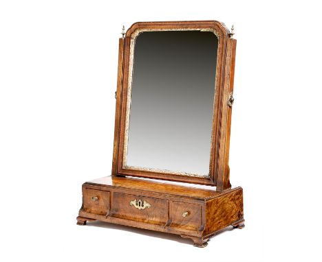 A George II walnut toilet mirror, with a bevelled arched plate within a carved gilt slip and a moulded frame, with turned bra