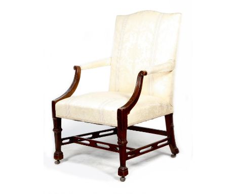 A George III mahogany Gainsborough armchair, upholstered in a cream damask fabric, with scroll arms carved with blind Gothic 