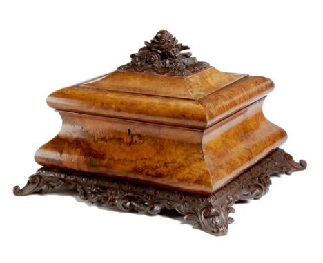 A Victorian walnut sarcophagus sewing box, with burr veneers, the hinged lid carved with flowers, acorns and leaves, revealin