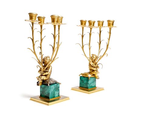 A pair of late 19th century ormolu and malachite four-light candelabra, each modelled with a cherub sat on a tasselled cushio