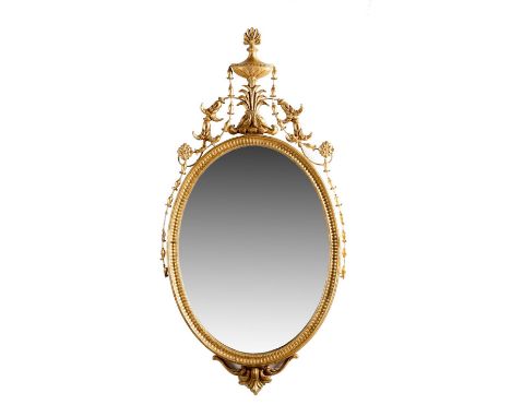 An Adam style giltwood wall mirror, with an oval plate within a fluted frame and with an urn surmount, 92 x 47cm. Provenance: