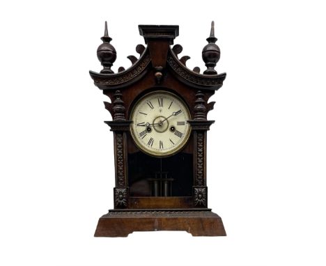  A German 19th century striking mantle clock in a wooden case on a canted plinth, curved top with carving and finials, 30hr J